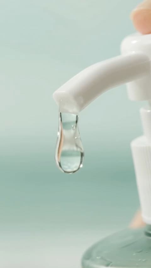 Skincare ad: a clear drop of Saltair body serum forming at the pump of a sea-green bottle
